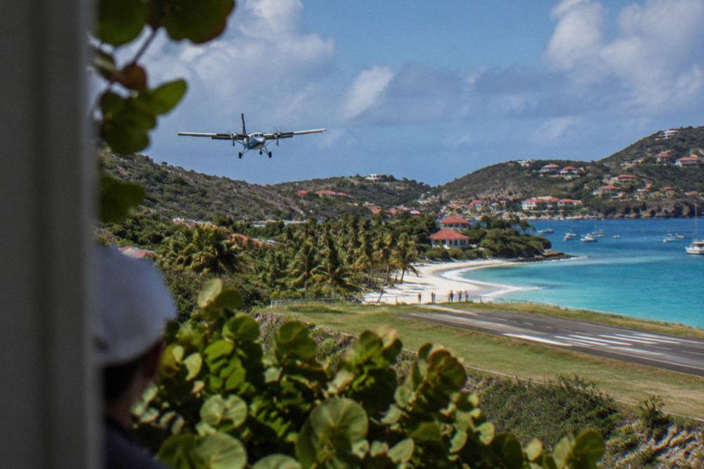 A small turboprop aircraft on a short runway beside a palm-lined beach