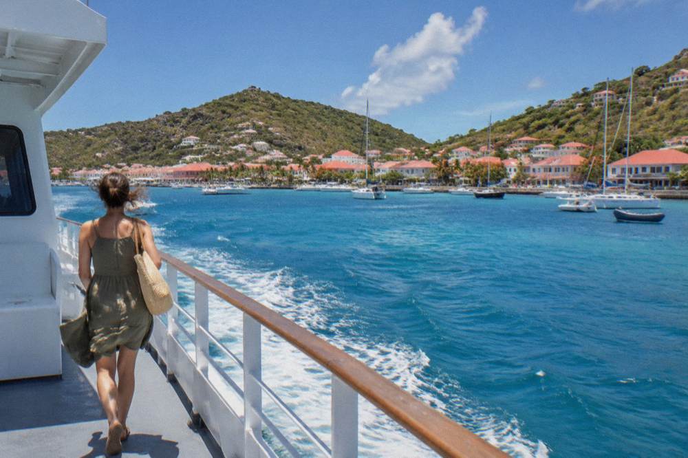 A ferry boat crossing open blue water toward an island coastline