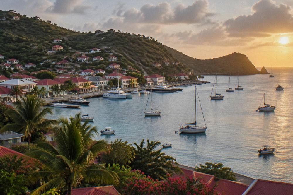 Sunset light on calm Caribbean water with the silhouette of a headland and anchored boats