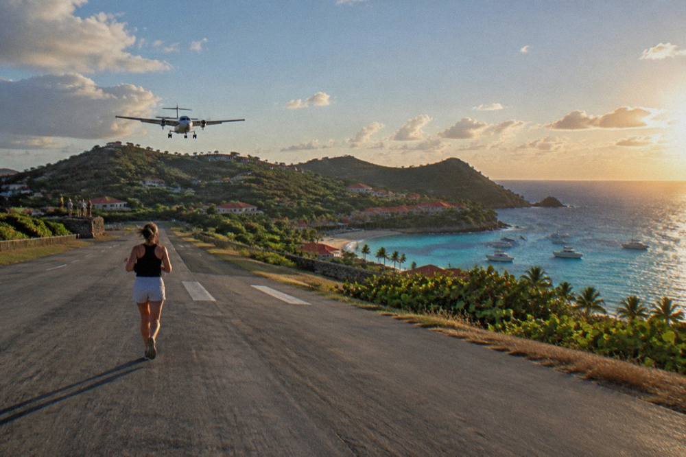 A small turboprop aircraft on a short runway beside turquoise water