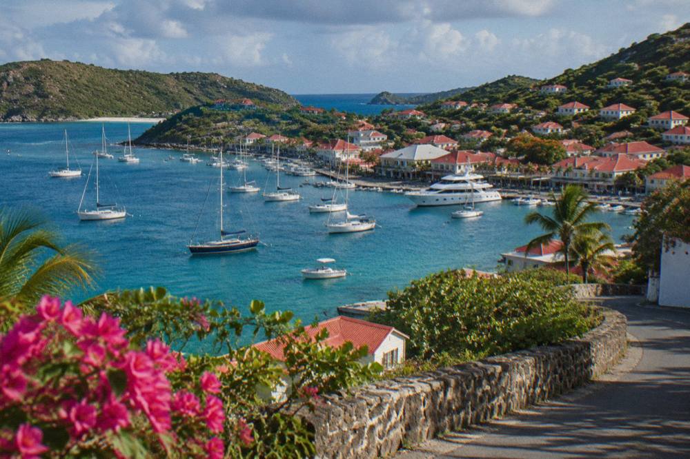 A wide south coast bay on St Barts seen from a hilltop road, sand curving between green headlands