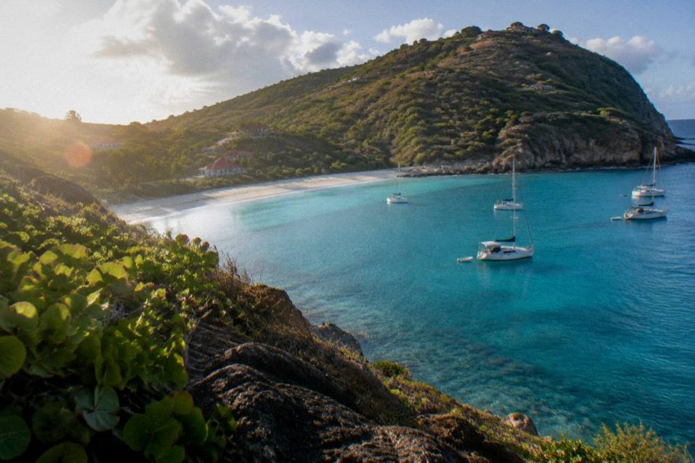 Colombier Bay on St Barts seen from a hillside, a boat at anchor in clear water below