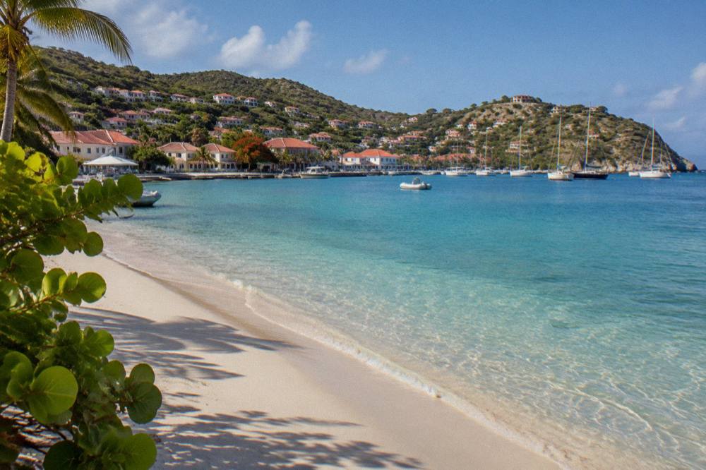 An empty stretch of public sand on St Barts in morning light with clear shallow water