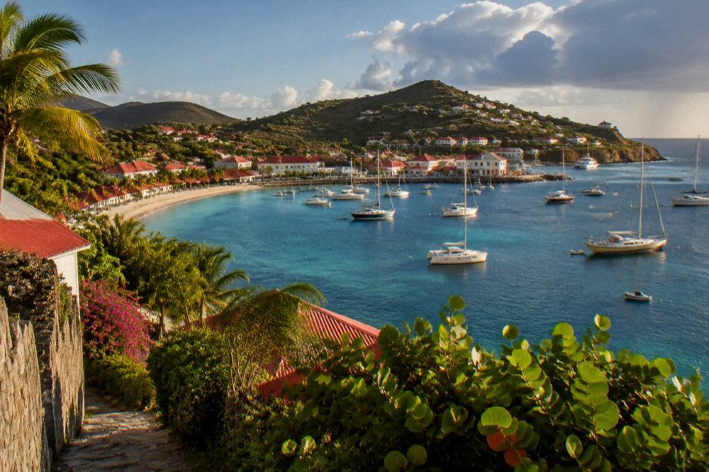 A walker's view down onto a crescent bay with boats at anchor in St Barts