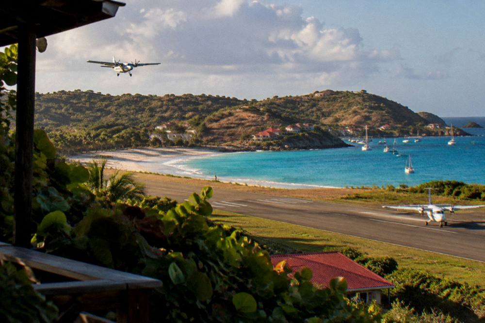 A small turboprop on the short runway at Gustaf III Airport with the beach beyond