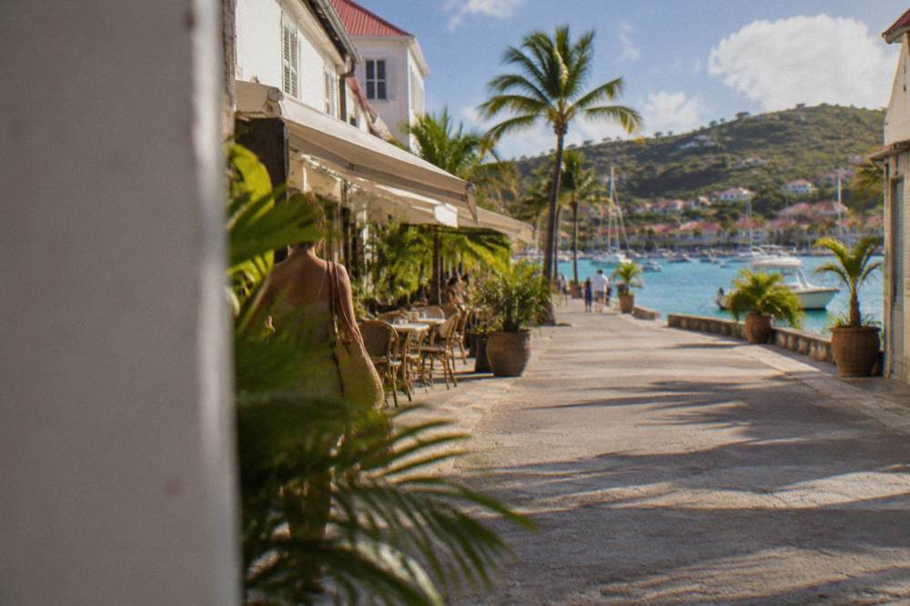 Narrow street of a small harbor town with white facades and palm trees