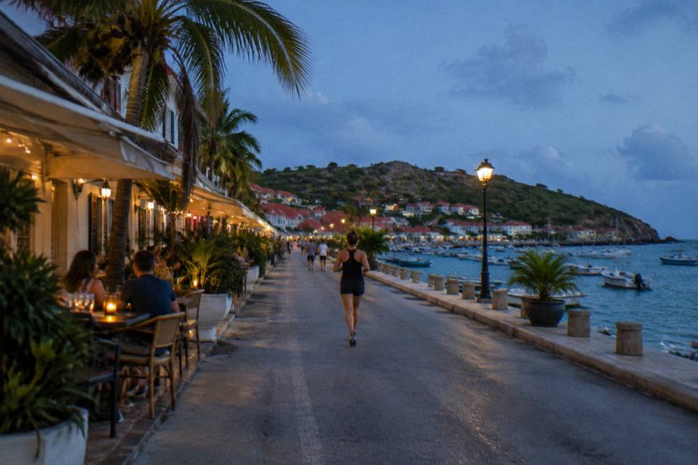 Diners at an open-air table beside palm trees in warm evening light