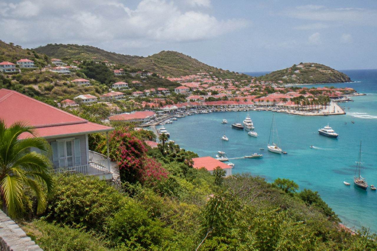 A small red-roofed hotel building above a turquoise bay on a green Caribbean hillside