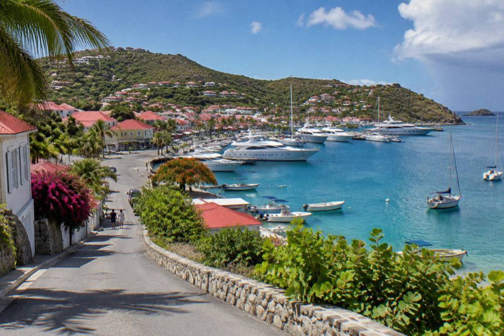 A narrow island road winding past low buildings toward a Caribbean bay