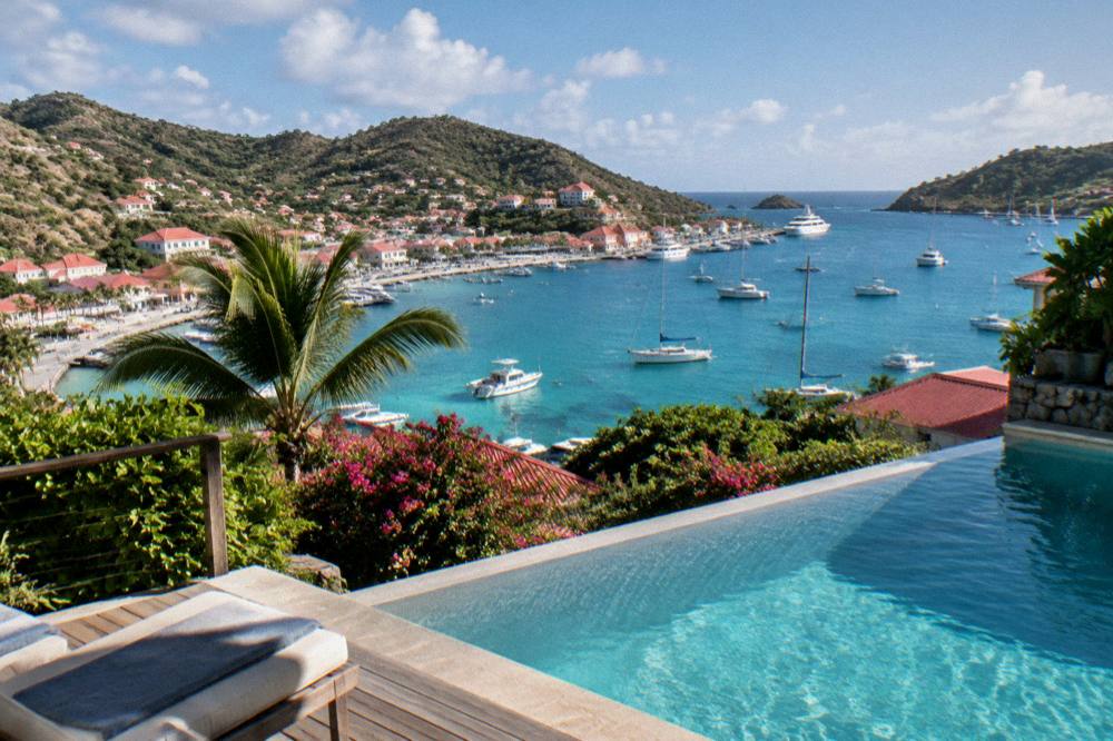 A hillside villa with a pool overlooking a Caribbean bay at late afternoon