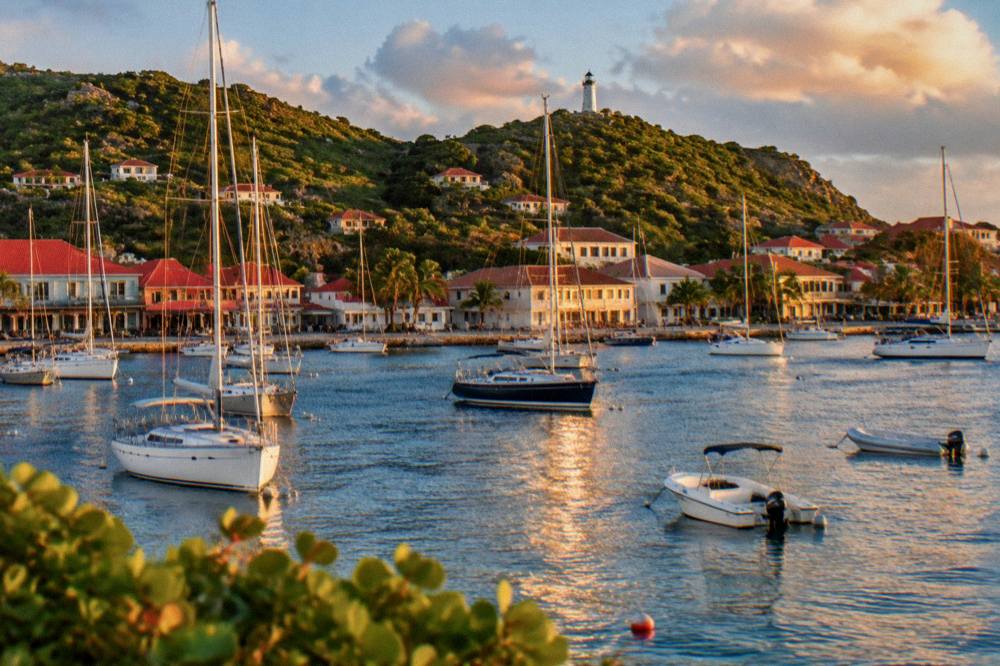 Gustavia harbour at golden hour with boats at anchor and red roofs along the shore