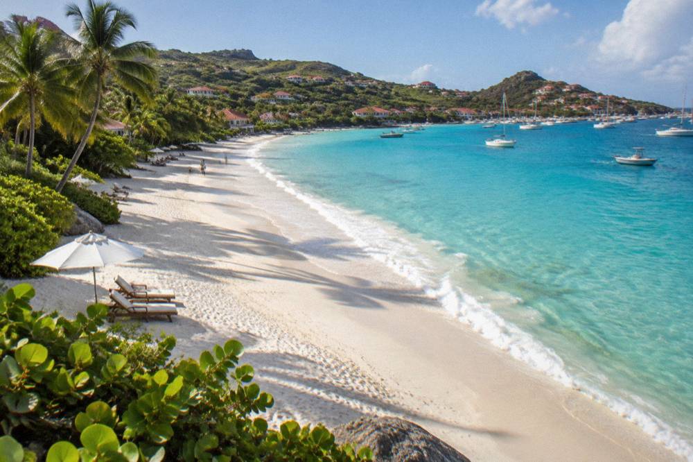 Sun loungers and an umbrella on white sand with calm clear water in the morning light