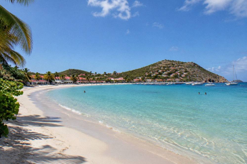 A sunny beach day on a Caribbean bay with white sand and clear shallow water