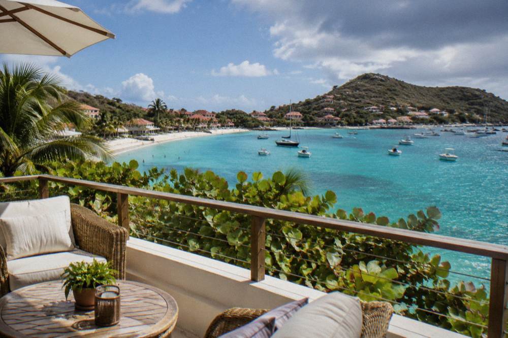 An elegant hotel terrace with rattan furniture overlooking a blue bay