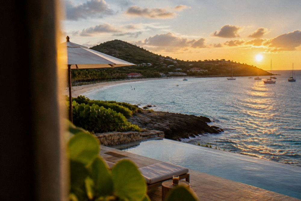 A Caribbean hotel exterior on a rocky point with the sea on both sides at sunset
