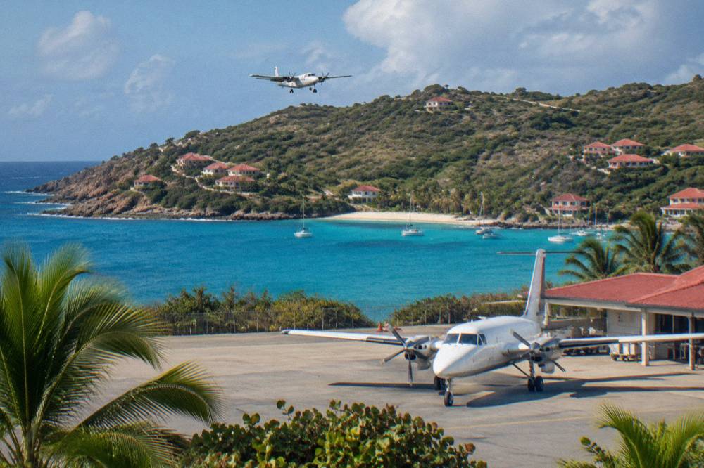 A twin-engine turboprop parked at a Caribbean airport terminal with warm evening light