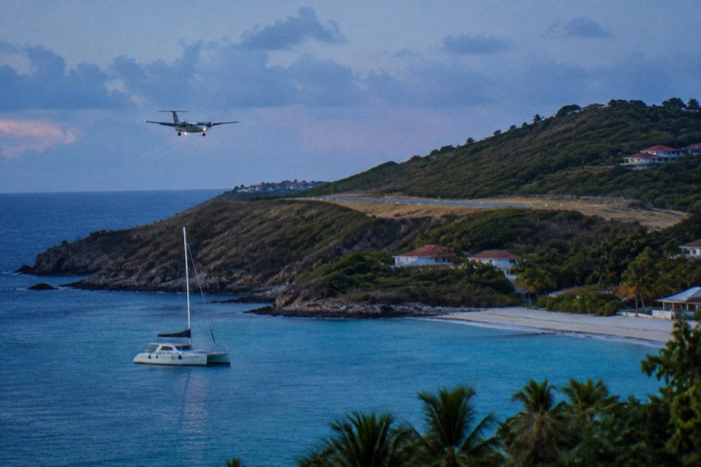 A sailing catamaran anchored in a quiet bay with green hills rising behind it in St Barts