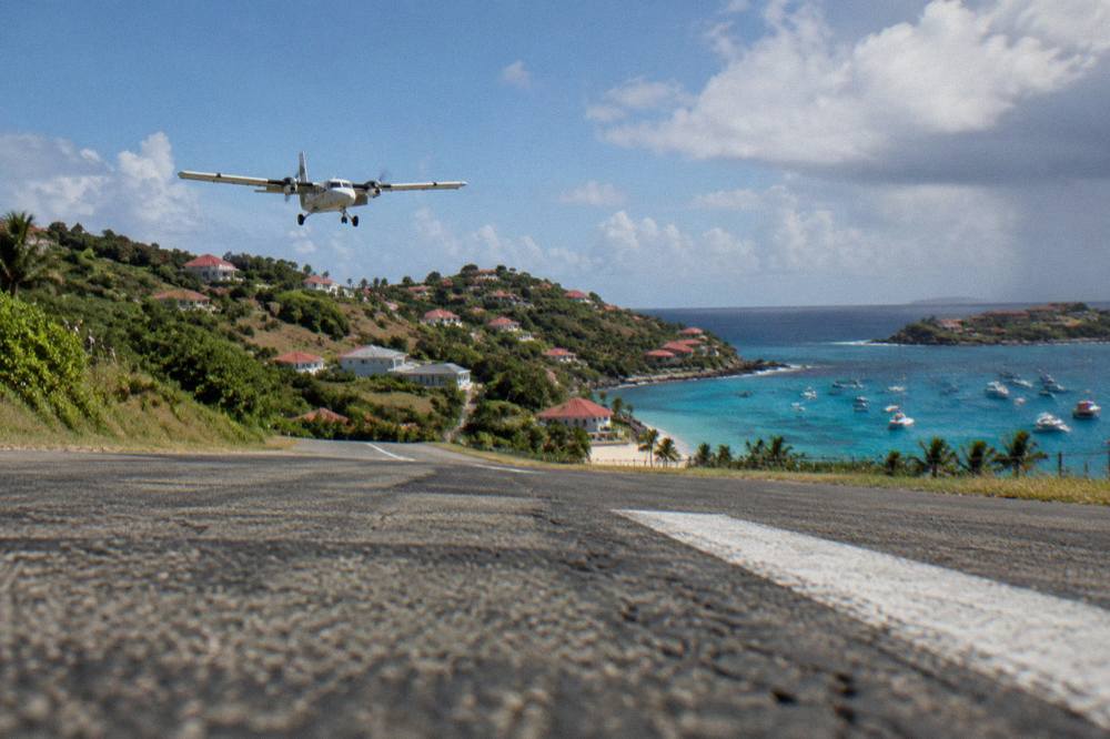 A hillside of white villas with red roofs descending toward a bright blue Caribbean bay