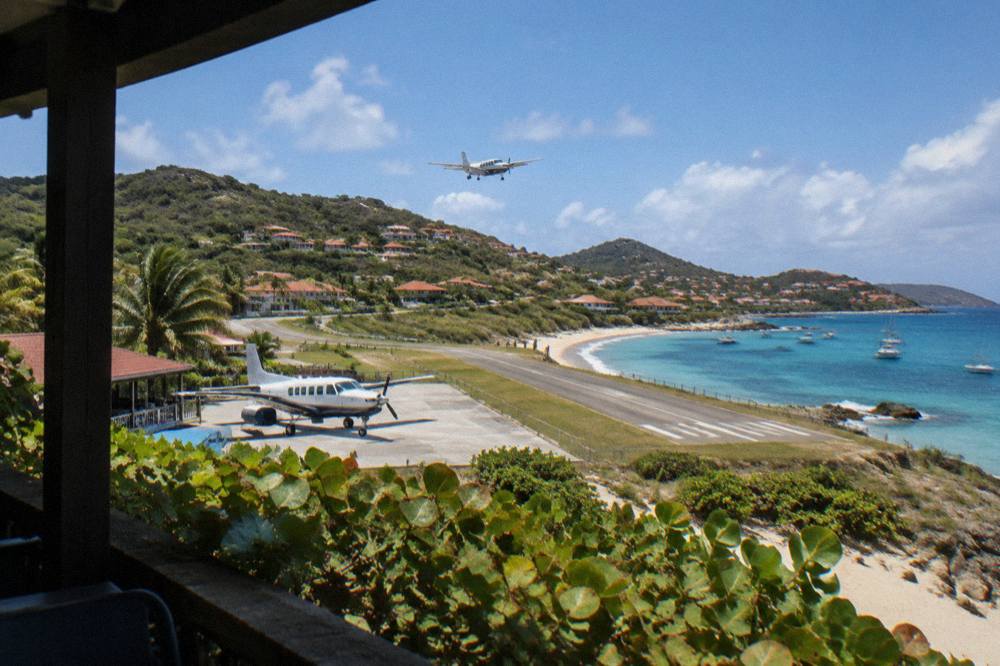 A single-engine turboprop parked at a small Caribbean airport terminal