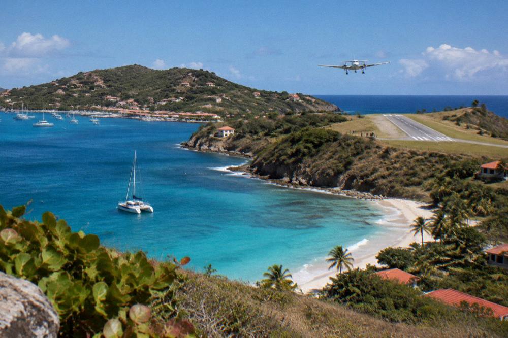 A sailing catamaran anchored in a quiet bay with a wooded hill behind it