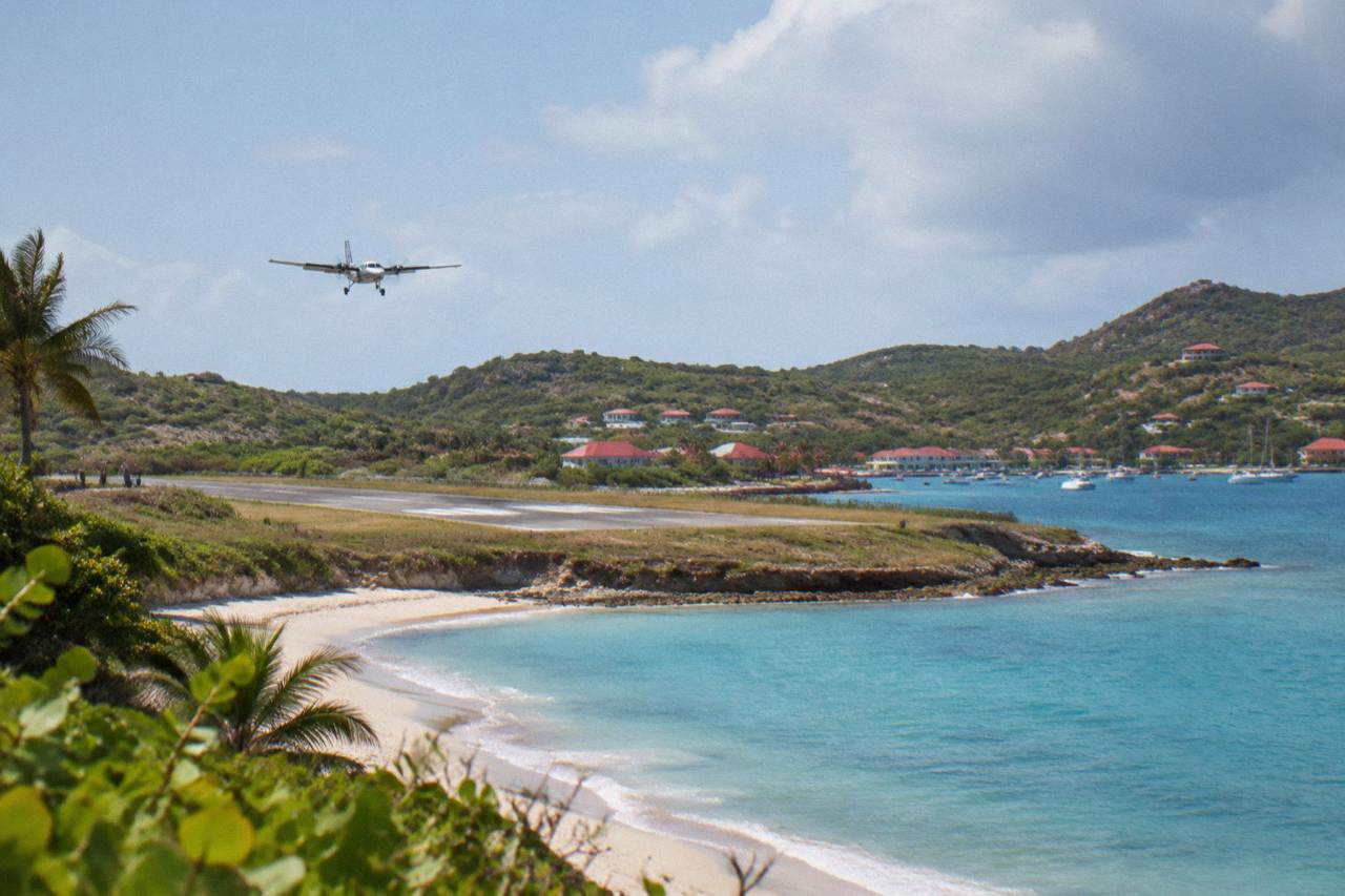 A small turboprop aircraft on a short Caribbean runway with green hills behind it