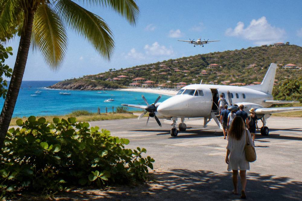 Passengers boarding a small aircraft on a warm airstrip beside palm trees