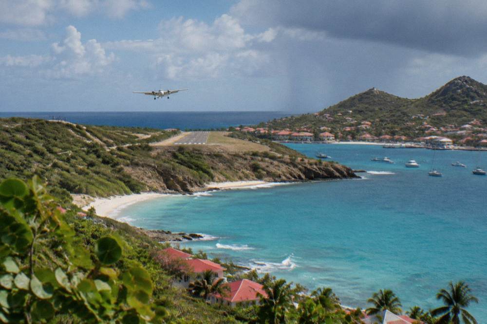 The short runway of a hillside Caribbean airport seen from above the water