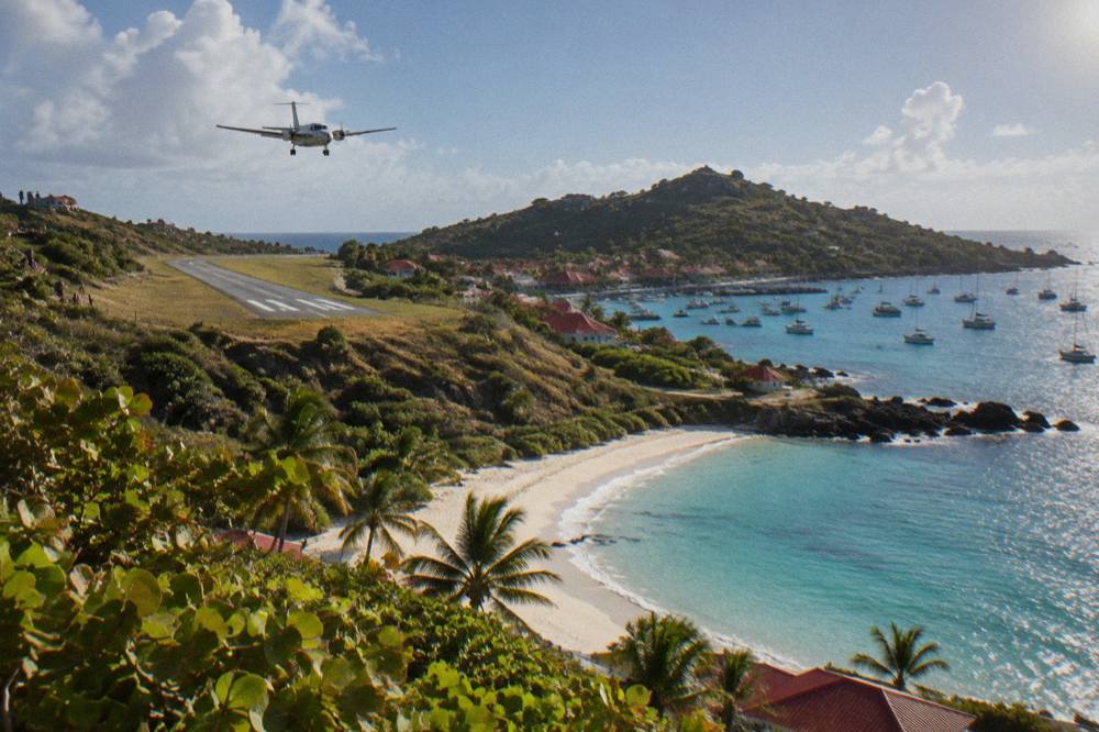 A quiet Caribbean beach with white sand, turquoise water and a wooded headland