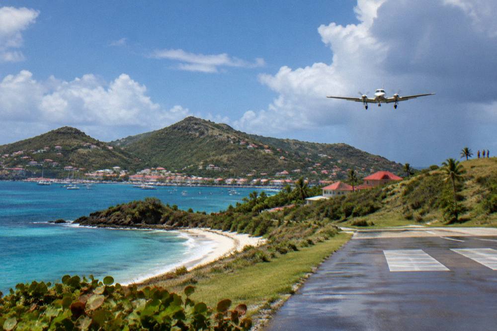 Red-roofed houses around a small Caribbean harbor with hills behind