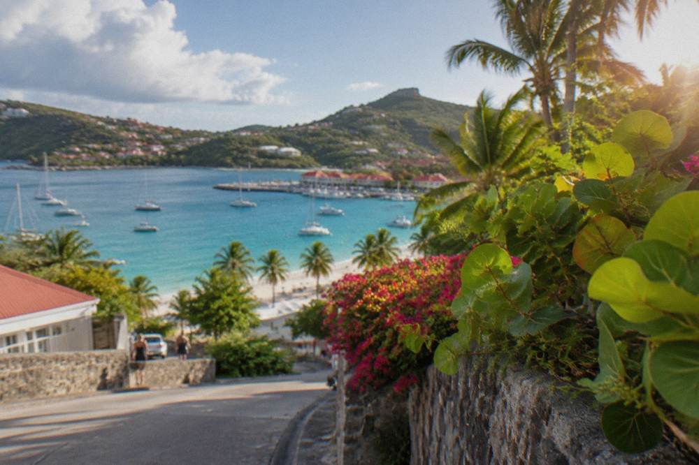 A steep coastal road descending toward a curved bay with anchored boats