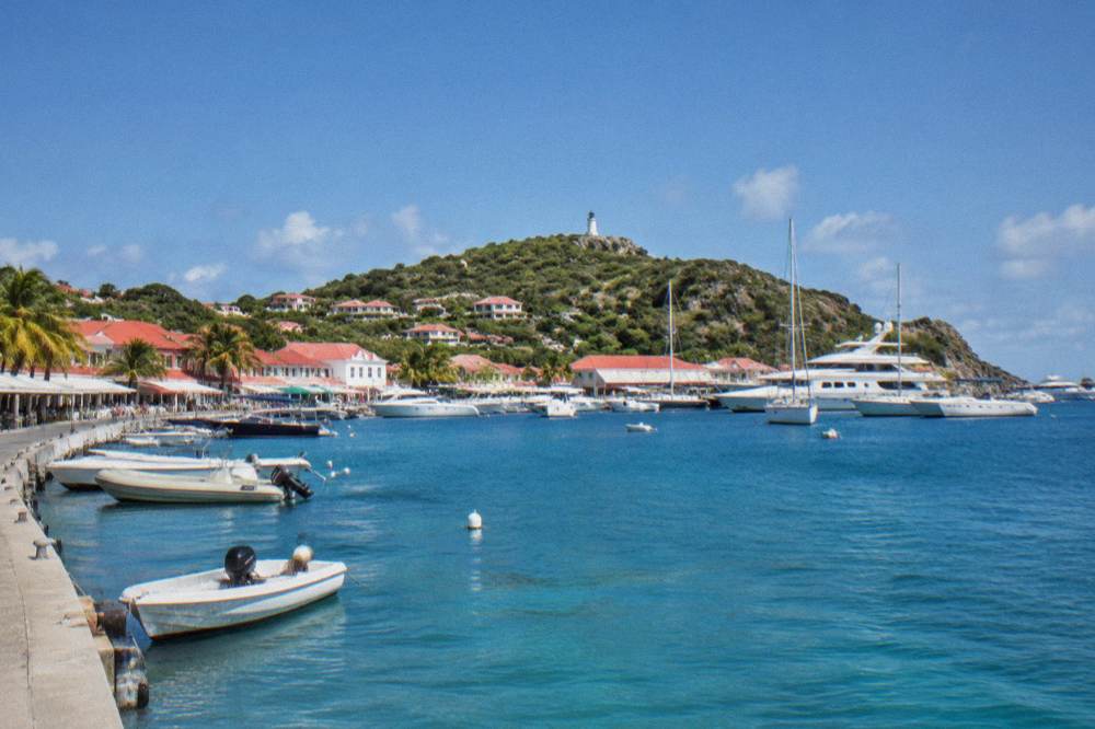 Gustavia harbour in St Barts with white buildings, red roofs and moored yachts under a clear sky