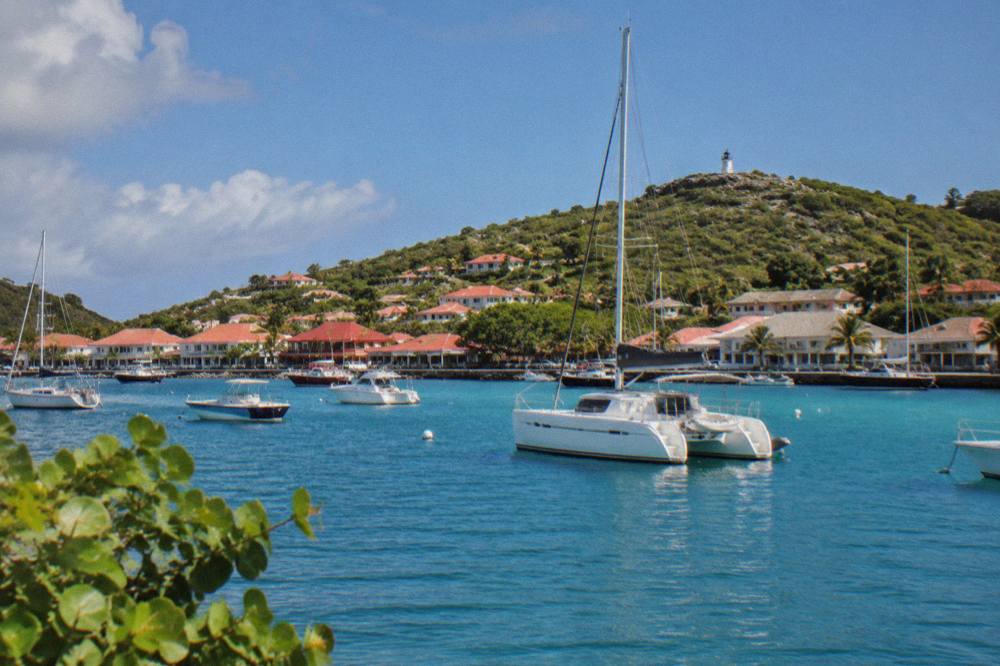 A catamaran at anchor in a quiet Caribbean bay fringed by green hills