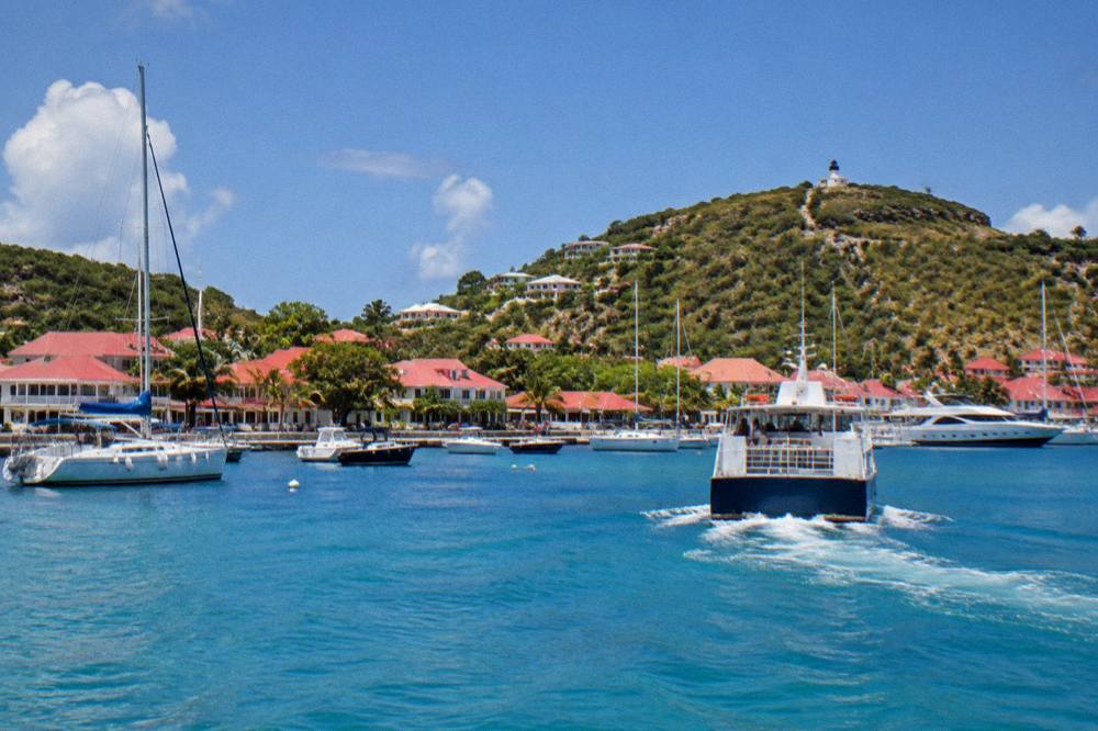 A ferry pulling away from a Caribbean dock at golden hour with hills behind