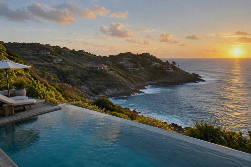 An infinity pool at the edge of a terrace overlooking the sea at dusk on a Caribbean headland