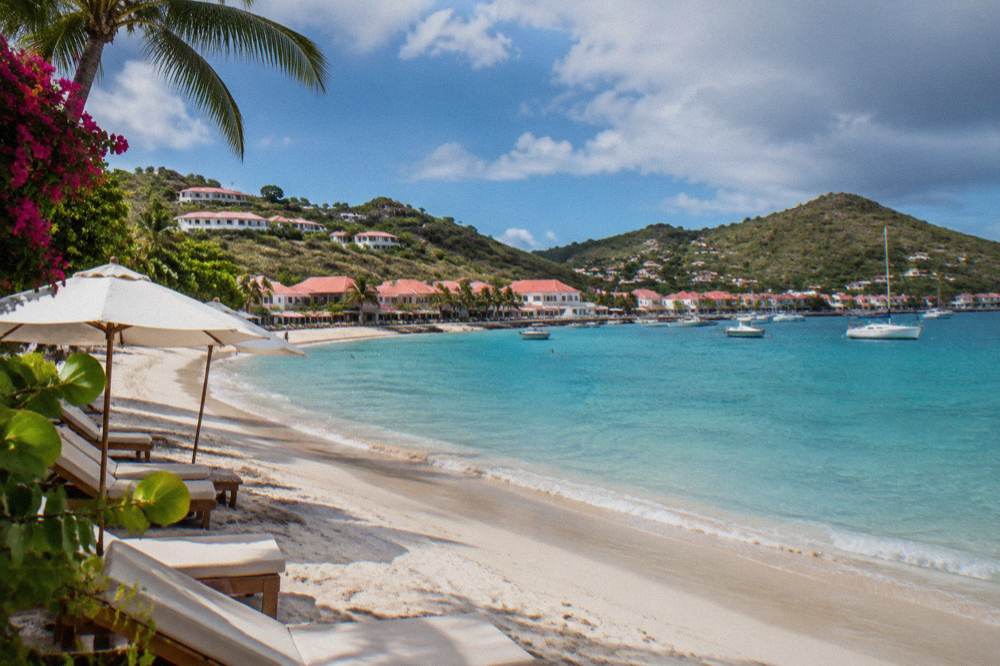 Sun loungers and umbrellas on a Caribbean beach beside calm turquoise water