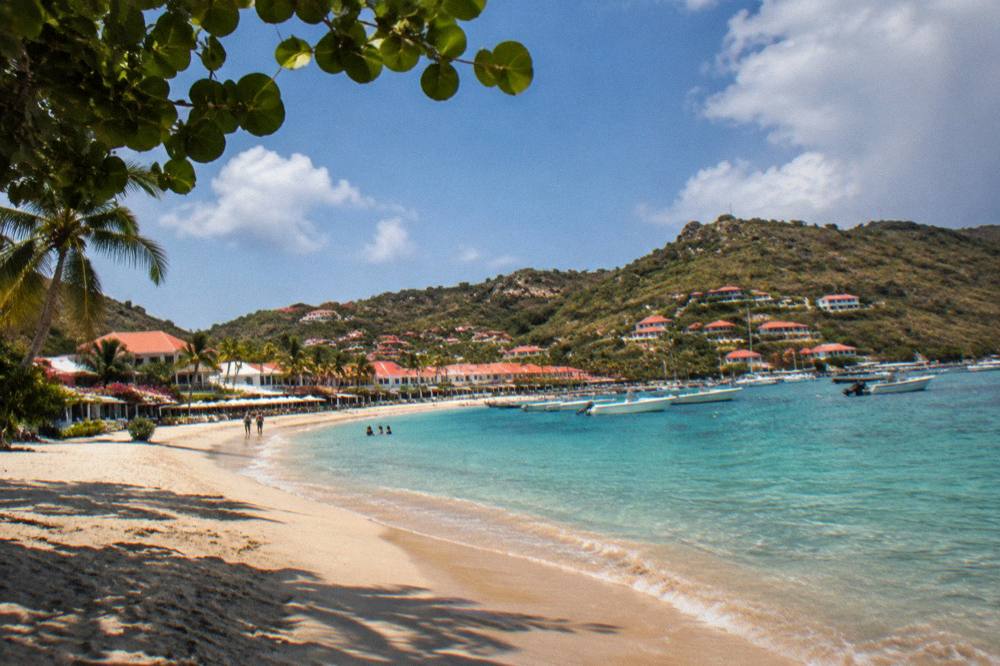 White resort buildings with red roofs above a curve of Caribbean sand