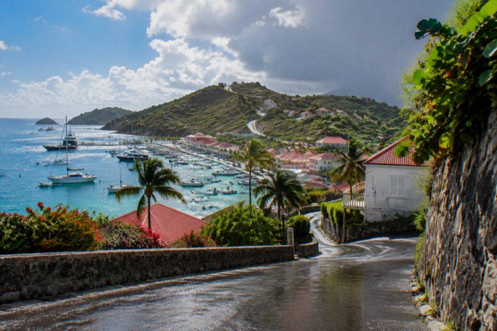 A narrow winding road climbing a green hillside above the sea