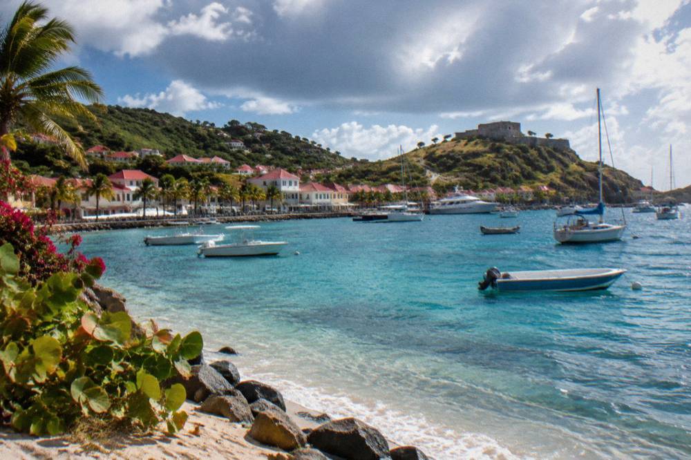 Stone fort ruins on a hillside overlooking a harbor and open sea