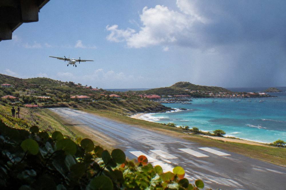 Small turboprop aircraft on a short runway between hills and a beach