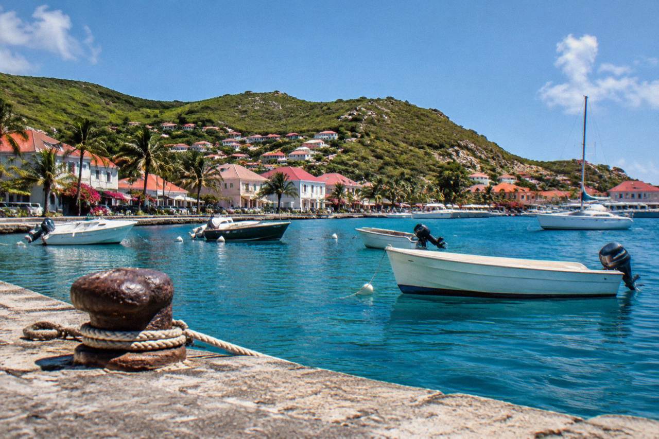 A calm harbour in Gustavia with small boats moored along a stone quay under a clear sky
