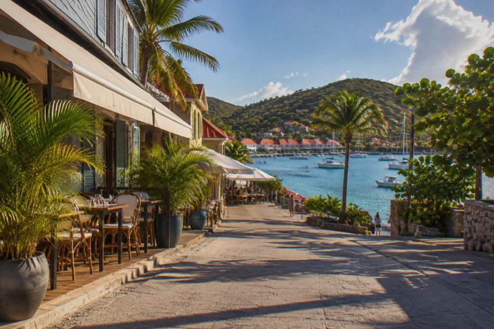Boats anchored in a quiet bay with green hills rising behind the shoreline of St Barts