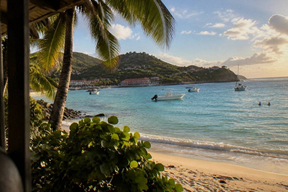 Sunlight on a turquoise Caribbean bay with scattered clouds over green hills
