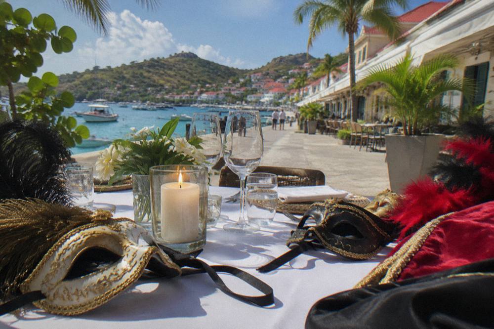 A candlelit dinner table with costumes and masks laid out for a themed night
