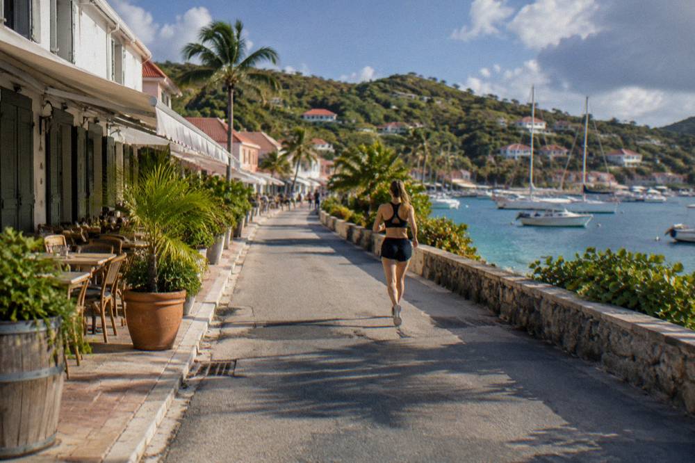 A narrow hillside road winding between low tropical vegetation on a small Caribbean island
