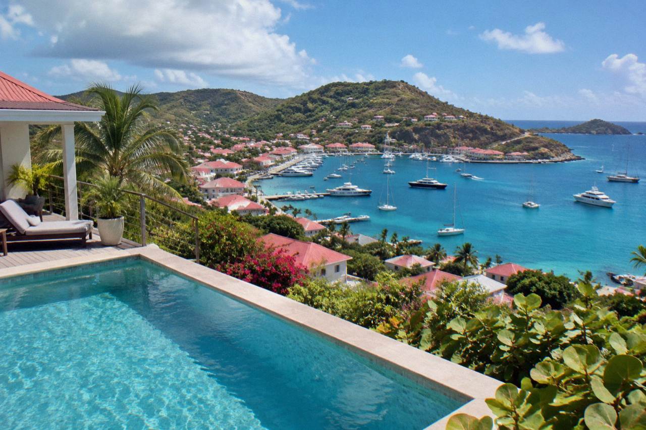A hillside villa with a terrace pool overlooking a Caribbean bay and sailboats