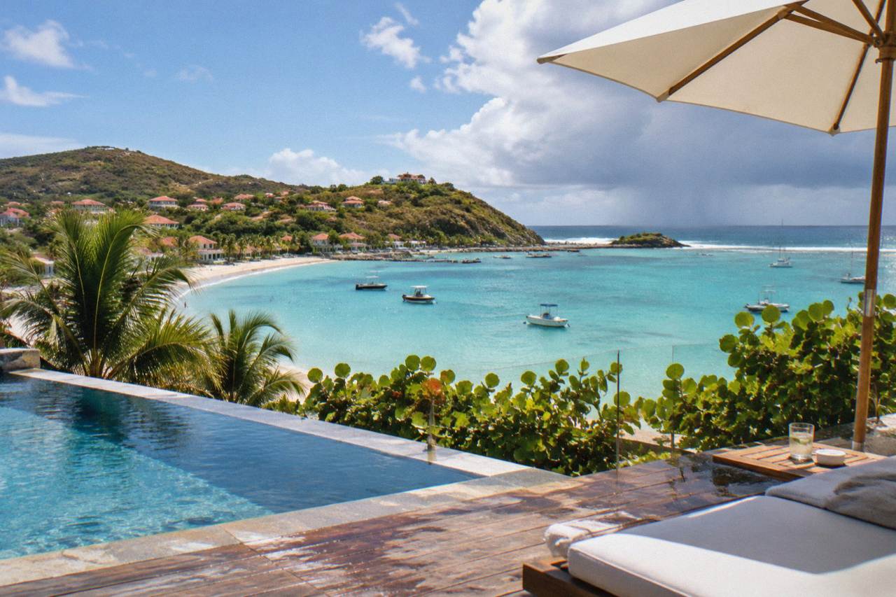 A luxury hotel terrace overlooking a calm turquoise bay on a Caribbean island