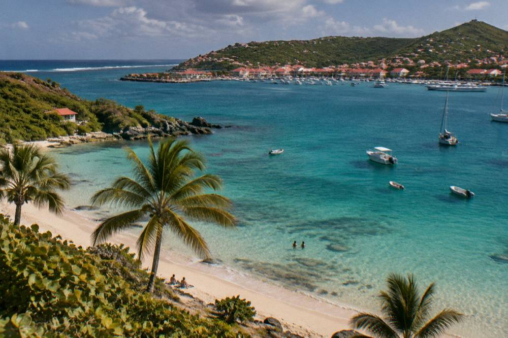 A harbour town with red roofs and white buildings seen across clear water