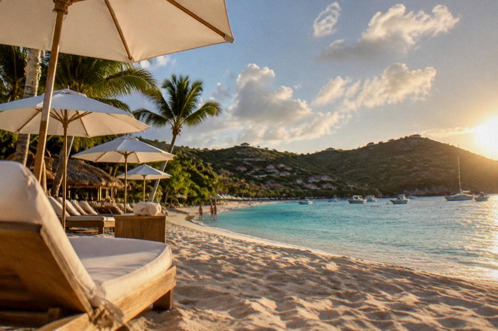 A hillside overlooking a bay with a long sandy beach and green slopes