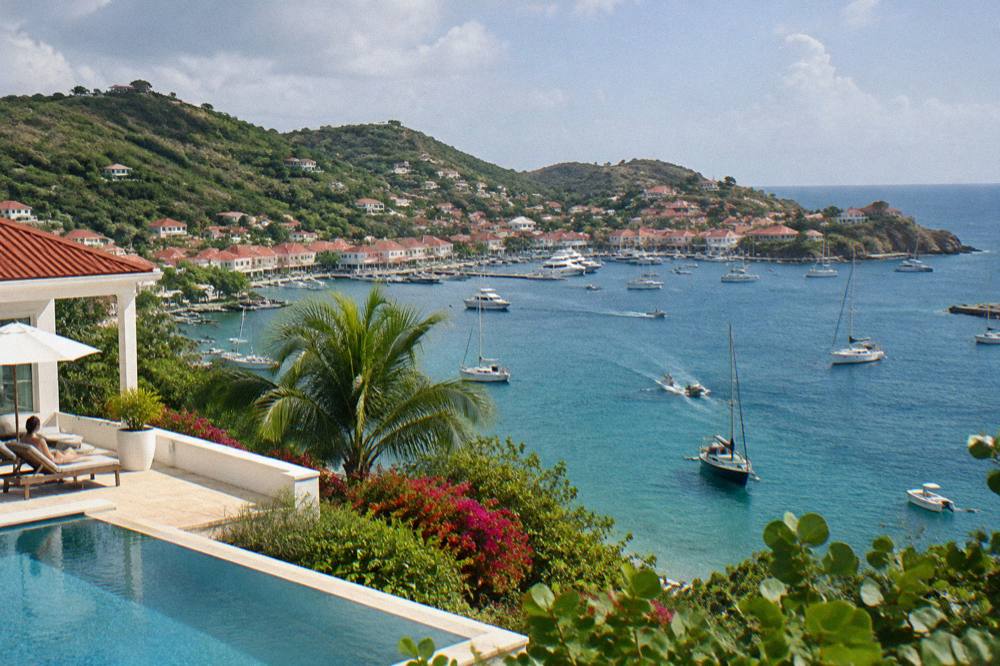 A whitewashed villa with a pool terrace overlooking green hills and sea