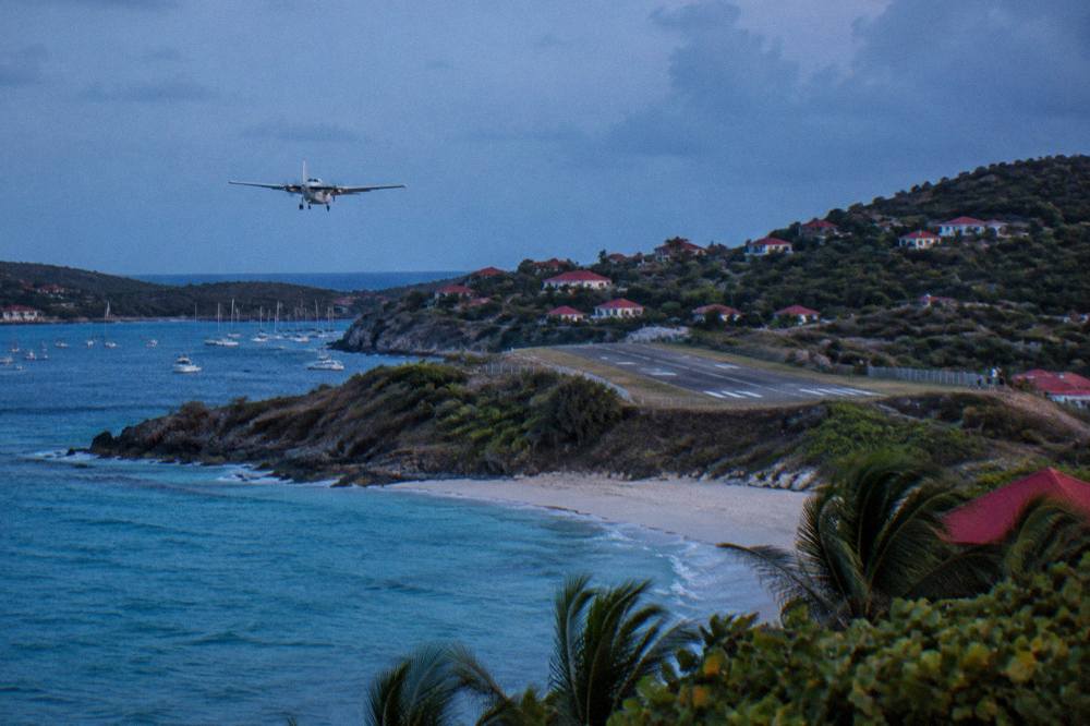 A small turboprop aircraft on a short runway beside a Caribbean beach